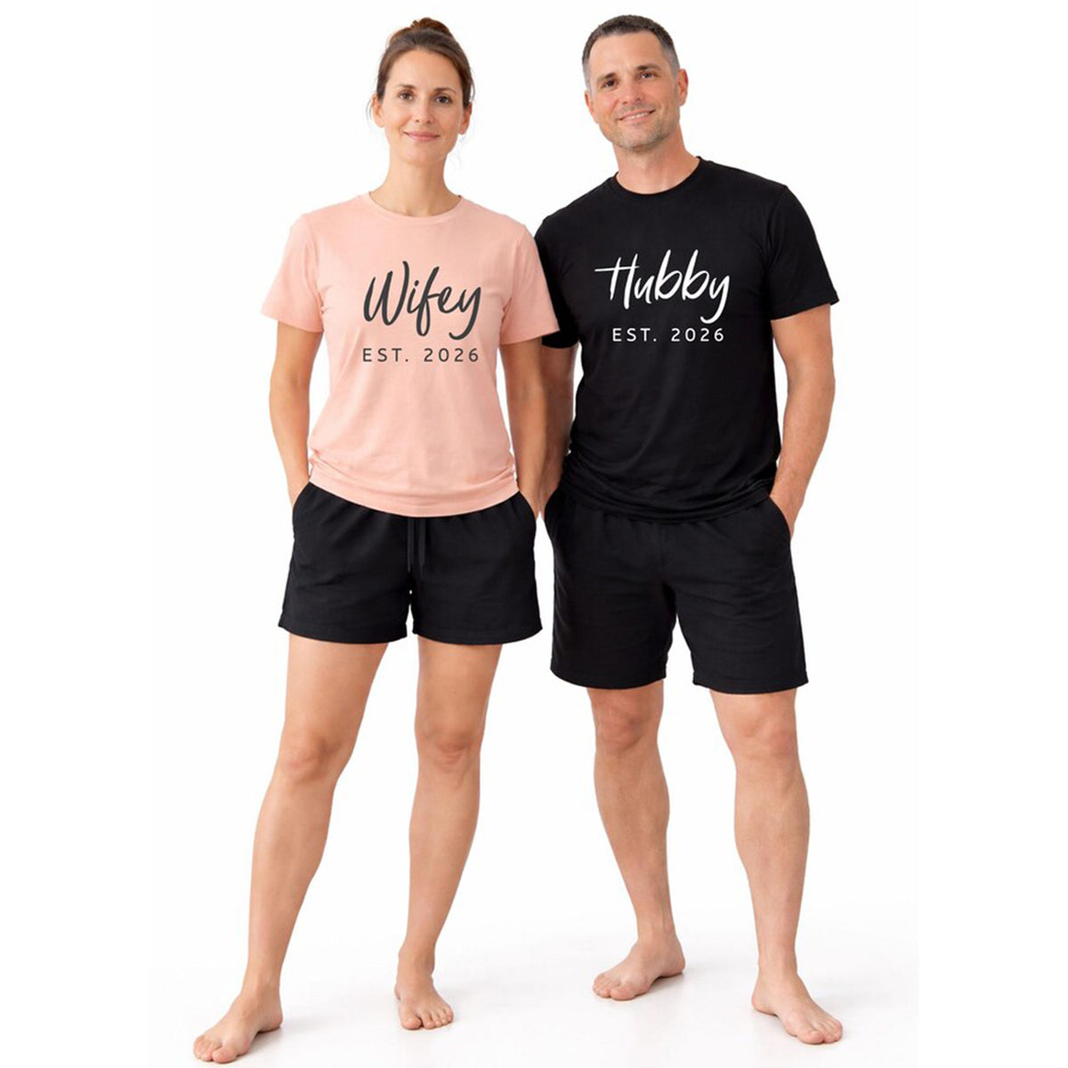 Couple wearing personalized Hubby and Wifey matching pajamas with custom year, short-sleeve t-shirts and black boxer shorts