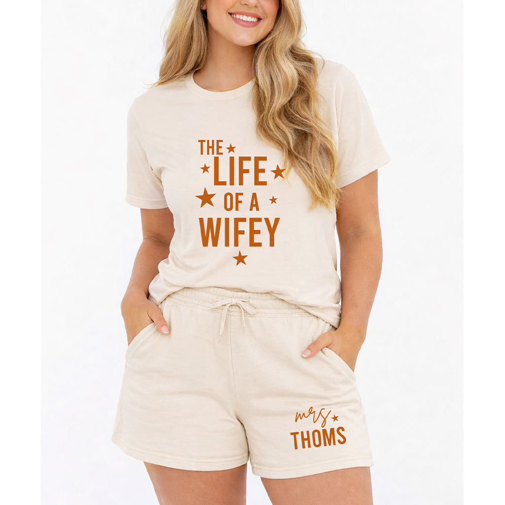 Personalized wife summer set in natural color with Life of a Wifey t shirt and custom Mrs family name shorts worn by female model on white background