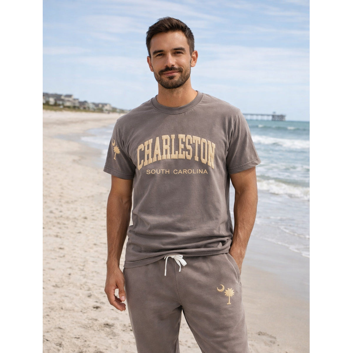 Man wearing Charleston South Carolina Comfort Colors puff print t-shirt and matching sweatpants with palm tree and crescent moon logo, casual beach outfit.