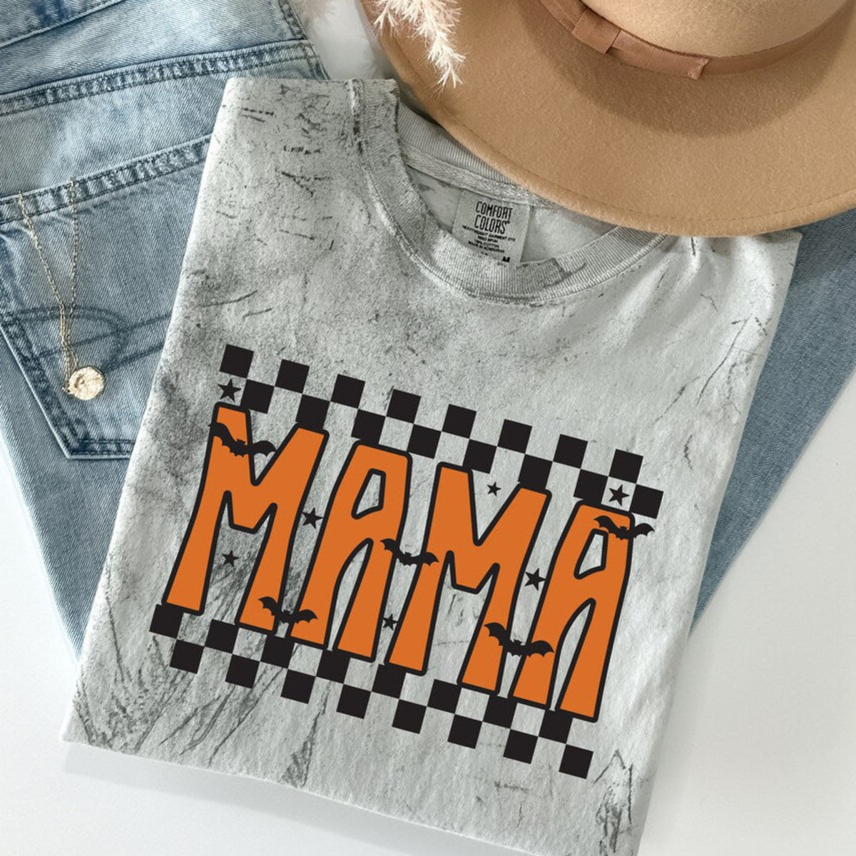 Folded Checkered Fall Mama Halloween shirt with orange Mama graphic, bats, stars, and black checkerboard design