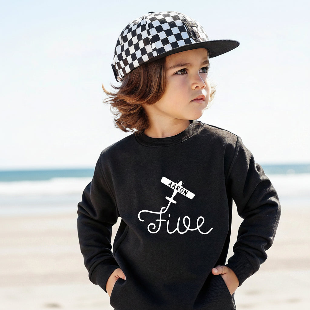 Boy wearing black personalized 5th birthday airplane sweatshirt with custom name outdoors
