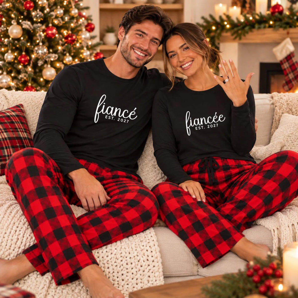 Engaged couple wearing personalized Fiancé and Fiancée long-sleeve shirts with matching flannel pajama pants, posing beside a decorated Christmas tree.