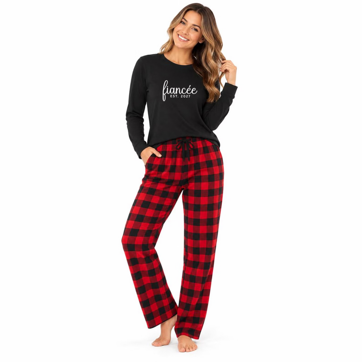 A woman wearing a long-sleeve jersey tee with “fiancée EST. 2027” lettering paired with red and black buffalo plaid flannel pajama pants.