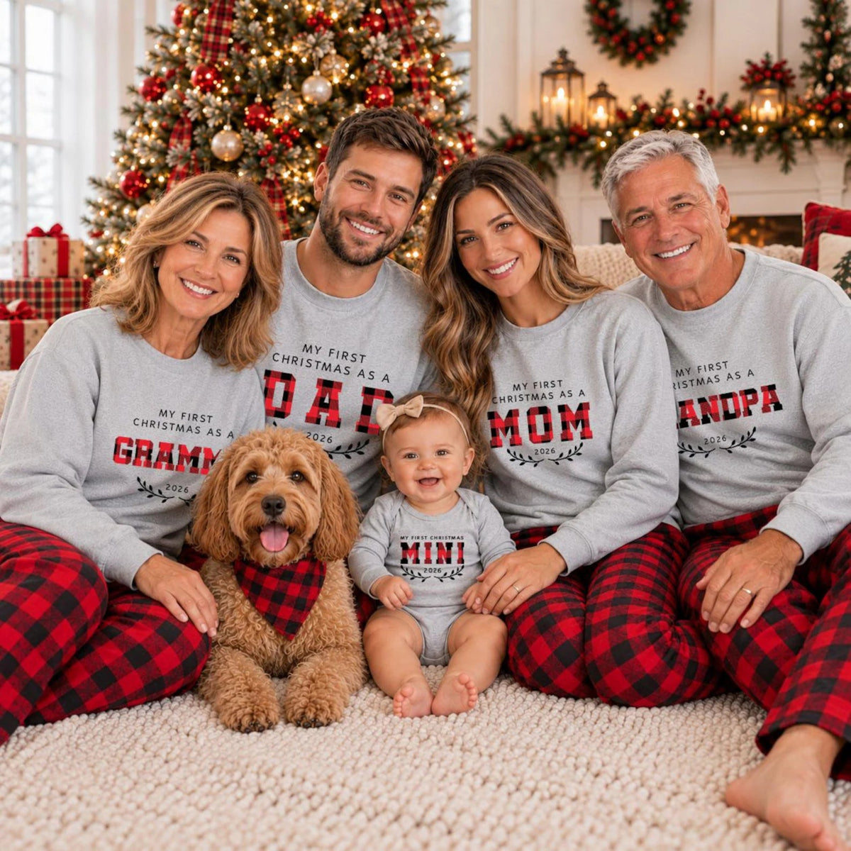 Family wearing matching First Christmas 2026 sweatshirts for Grandma, Grandpa, Dad, Mom, and Mini, with red and black buffalo plaid pajama pants, posing with their dog in a cozy Christmas living room.