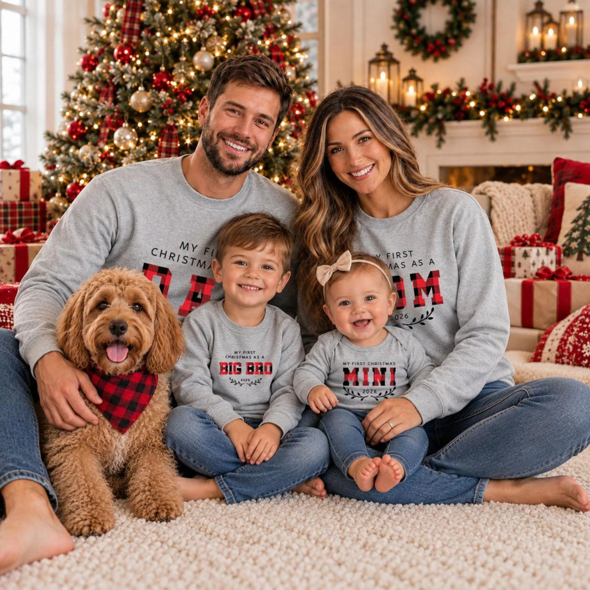 Family wearing matching First Christmas 2026 sweatshirts for Mom, Dad, Big Bro, and Mini, sitting together with their dog in a cozy Christmas living room.