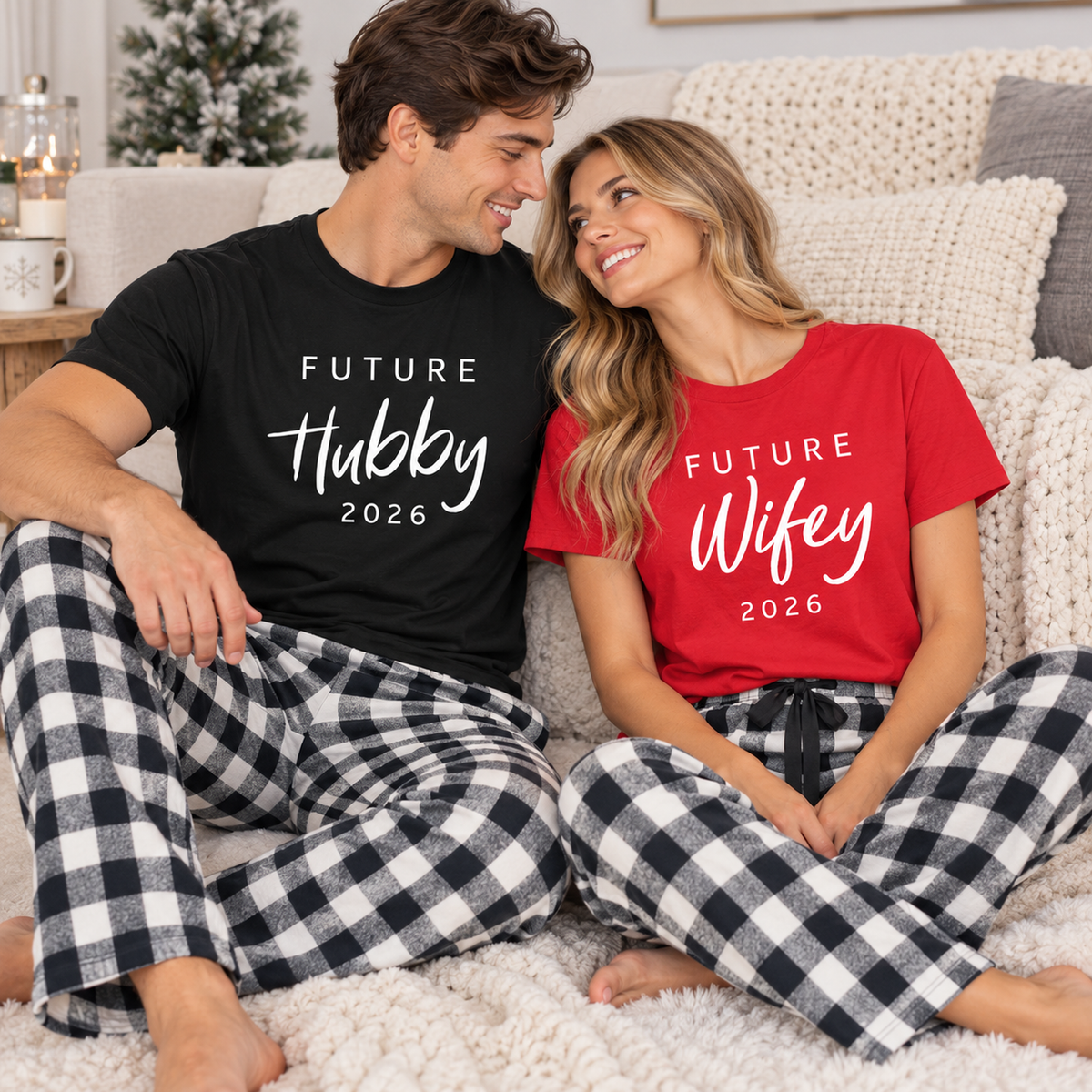 Young couple relaxing together in a cozy living room wearing matching Future Hubby and Future Wifey T-shirts with 2026 prints and black-and-white buffalo plaid flannel pajama pants.