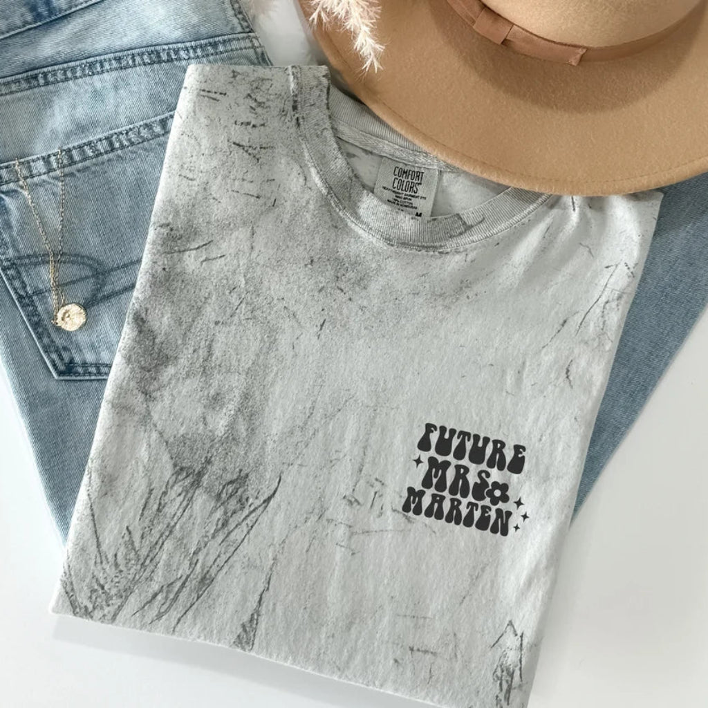 Personalized garment-dyed T-shirt with Future Mrs. and custom name chest print, styled with denim jeans and a hat.