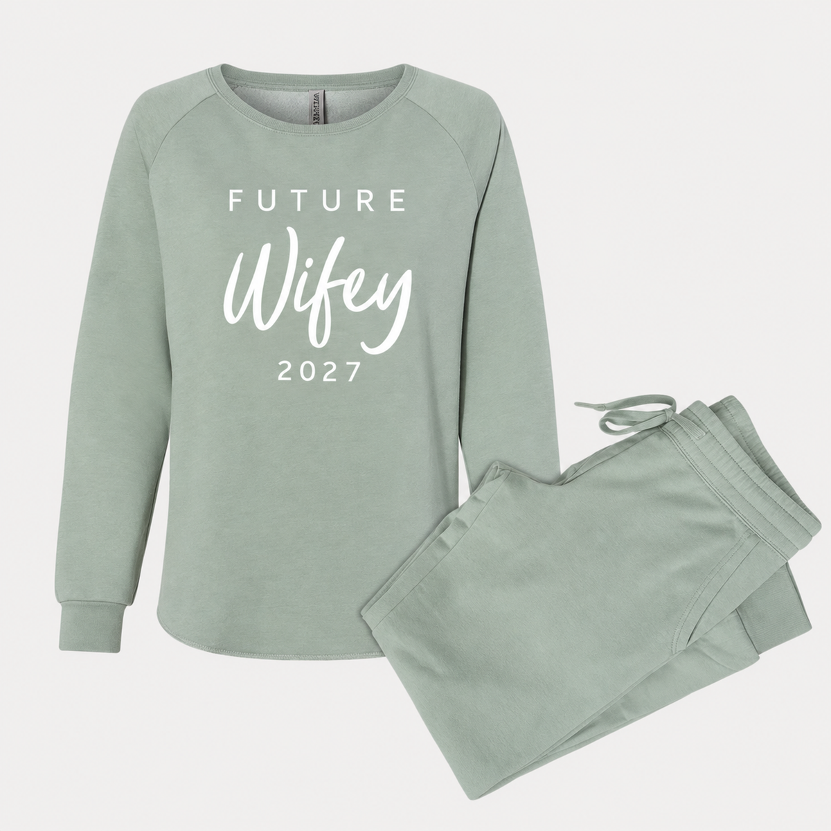 Sage Future Wifey sweatshirt and matching jogger sweatpants featuring white script lettering and the year 2027, arranged in a clean studio product photo.