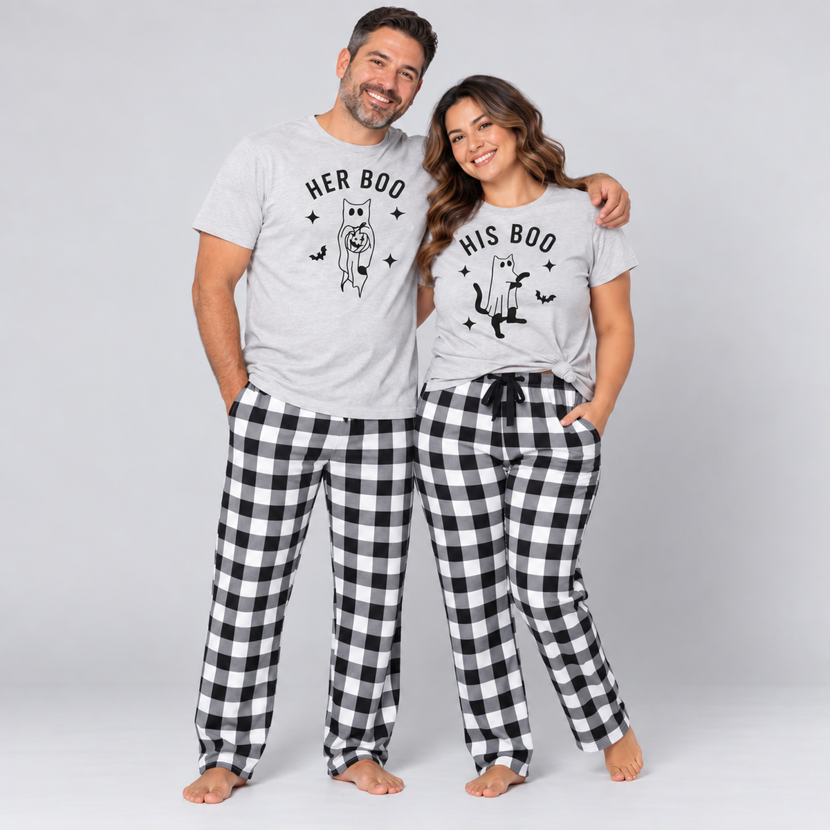 Couple wearing matching Her Boo and His Boo Halloween pajamas with cat ghost t-shirts and black-and-white checkered flannel pants in a light gray studio