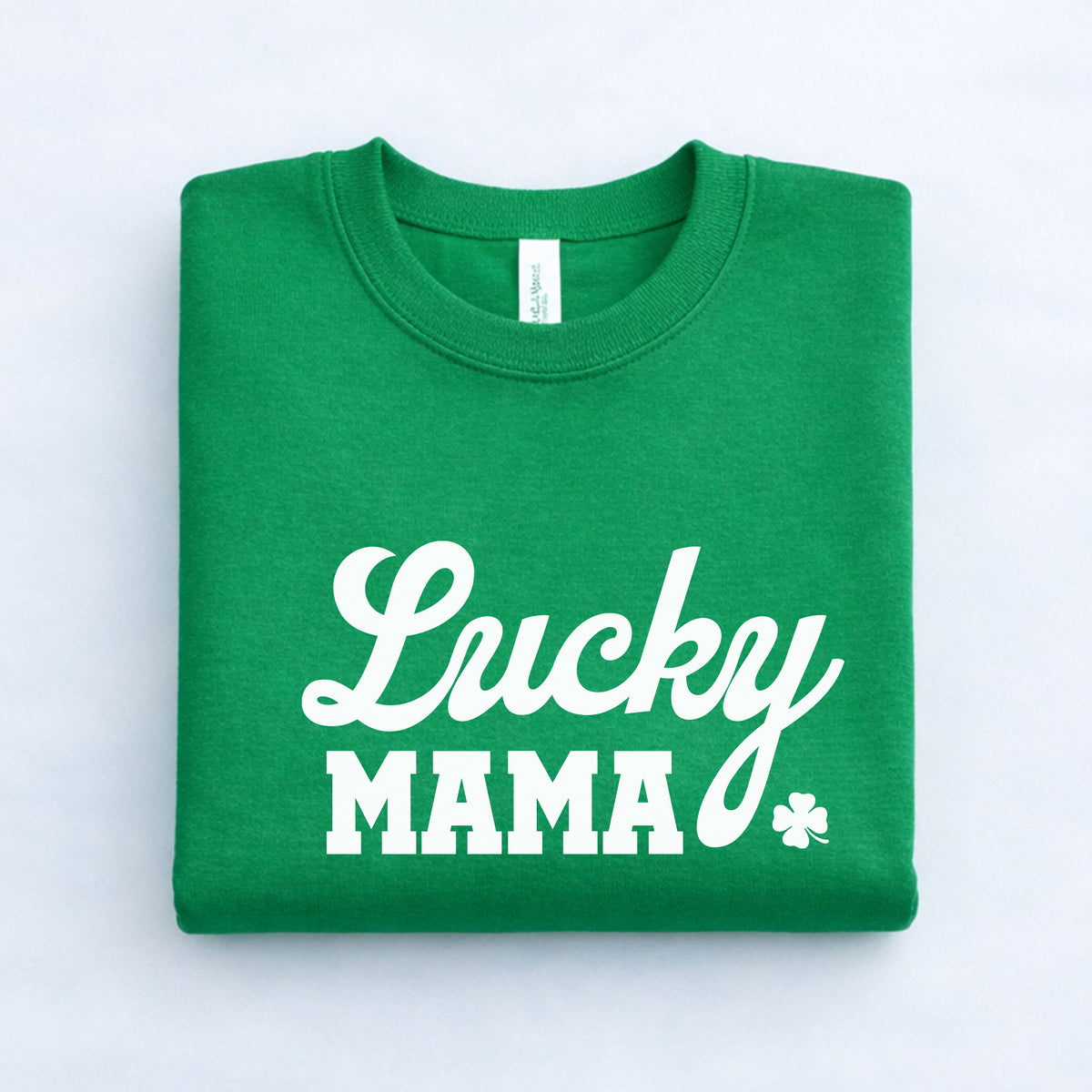 Green Lucky Mama St. Patrick’s Day sweatshirt with white shamrock print, folded flat lay product photo.