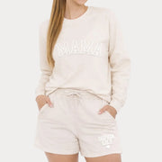 Woman wearing bone color Mama crewneck sweatshirt and personalized sweatshorts with custom kids names, casual lounge set.