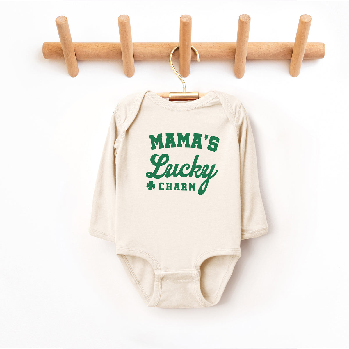 Natural baby long sleeve bodysuit with Mama’s Lucky Charm green St. Patrick’s Day print on hanger.