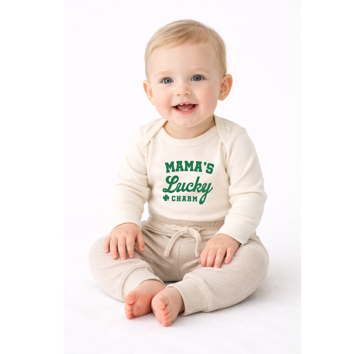 Smiling baby wearing Mama’s Lucky Charm long sleeve St. Patrick’s Day bodysuit in natural color.