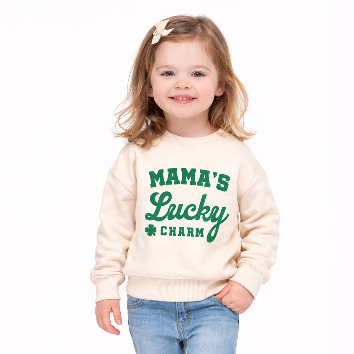 Toddler girl wearing natural Mama’s Lucky Charm St. Patrick’s Day sweatshirt with green shamrock print.