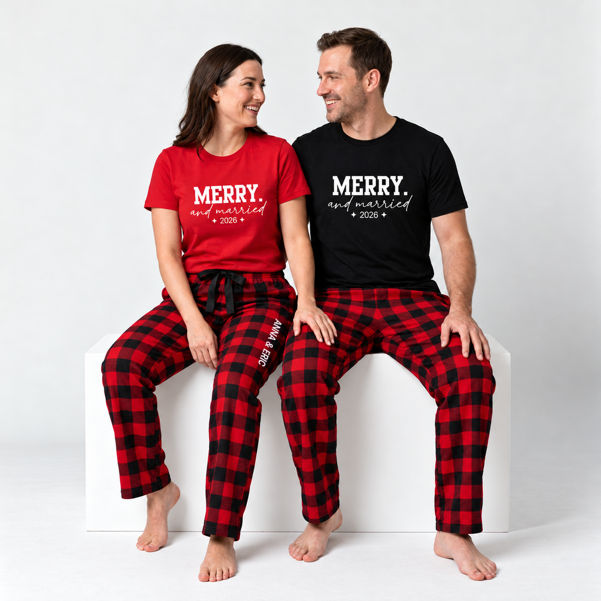 Couple wearing matching Merry and Married 2026 T-shirts with personalized red and black plaid pajama pants featuring ANNA & ERIC lettering.