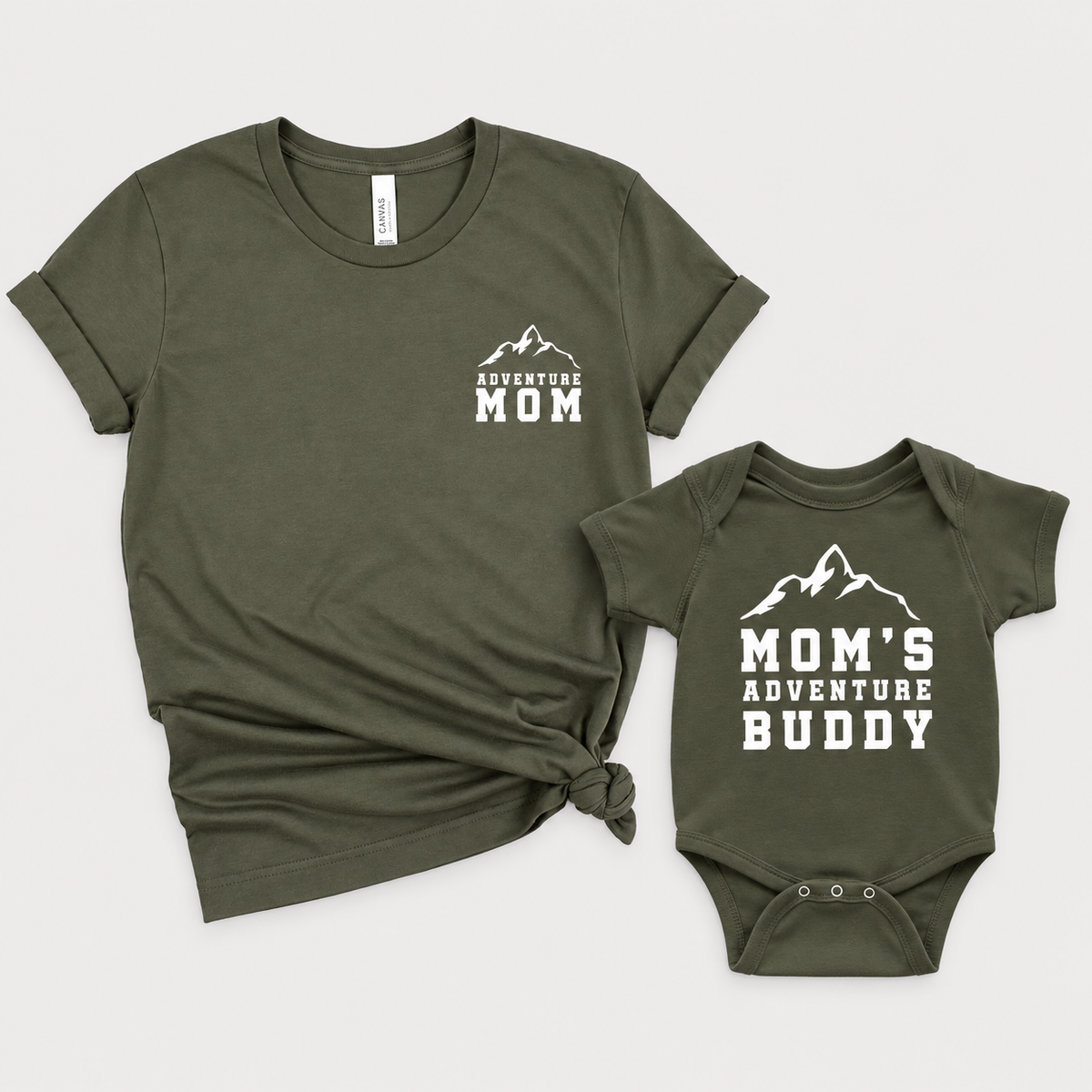 Military Green mom T-shirt and baby bodysuit with white mountain graphics and “Adventure Mom” and “Mom’s Adventure Buddy” lettering.
