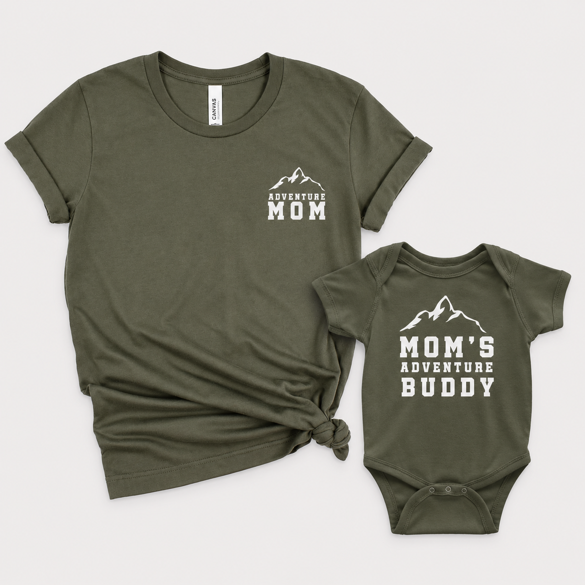 Military Green mom T-shirt and baby bodysuit with white mountain graphics and “Adventure Mom” and “Mom’s Adventure Buddy” lettering.
