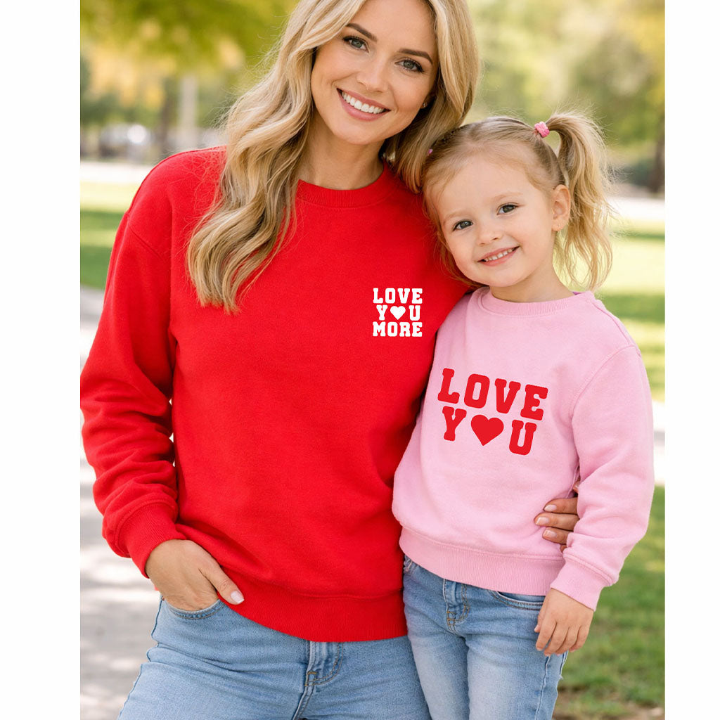 Mom and daughter wearing matching “Love You More” and “Love You” sweatshirts in an outdoor park setting