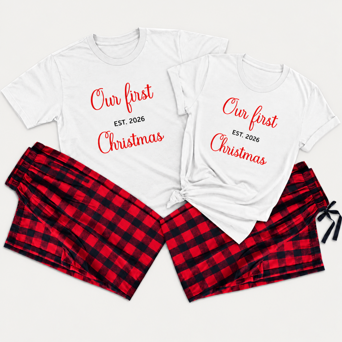 Personalized matching Christmas pajamas featuring two white T-shirts printed with “Our First Christmas” and “EST. 2026,” paired with red and black buffalo plaid flannel pajama pants in a clean studio flat lay.