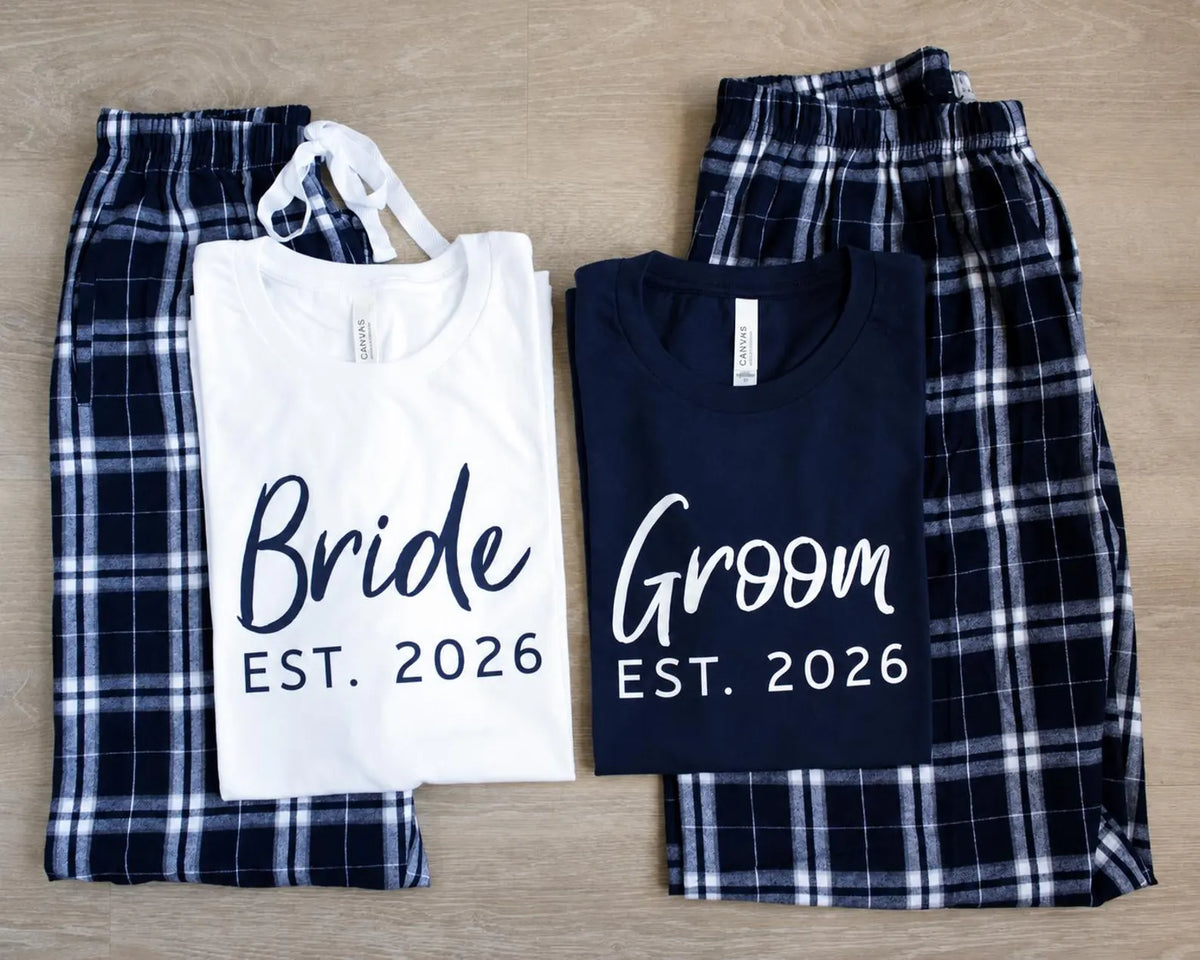 White Bride and navy blue Groom T-shirts with EST. 2026 prints, arranged over matching Navy-Silver plaid pajama pants.