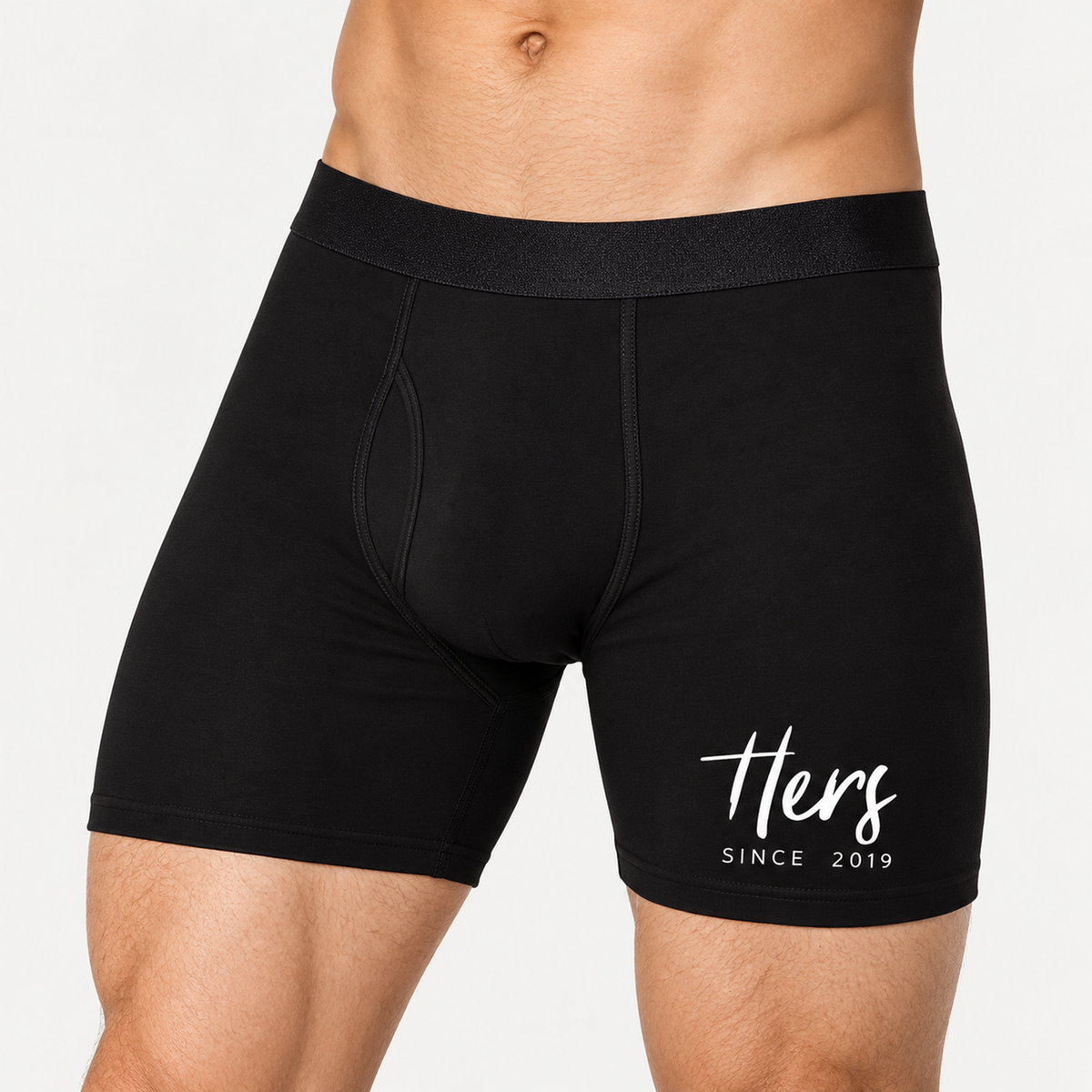 Men’s boxer briefs featuring the white script “Hers” and the year 2019, photographed in a clean studio setting.