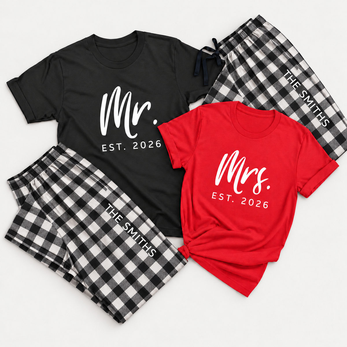 Personalized Mr. and Mrs. matching pajamas featuring 2026 T-shirt designs and black-and-white buffalo plaid flannel pajama pants with custom last name lettering, arranged in a clean studio flat lay.