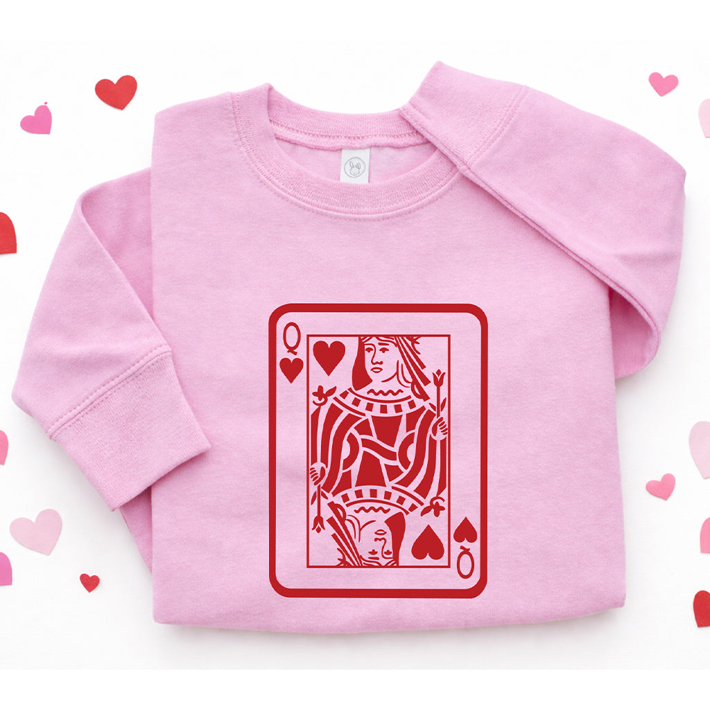 Pink kids Valentine’s Day sweatshirt with Queen card design, shown on pink background decorated with hearts