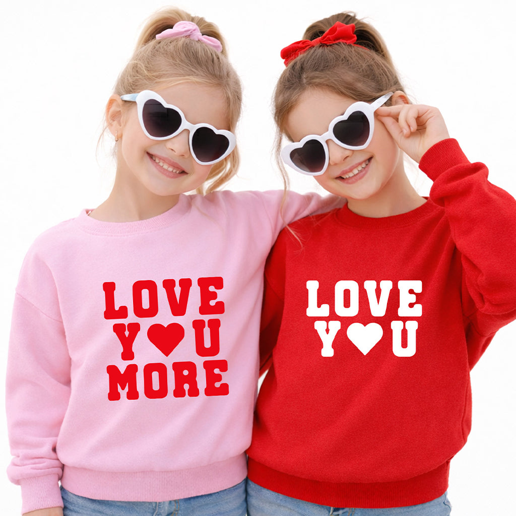 Two sisters wearing matching “Love You” sweatshirts in red and pink on white background