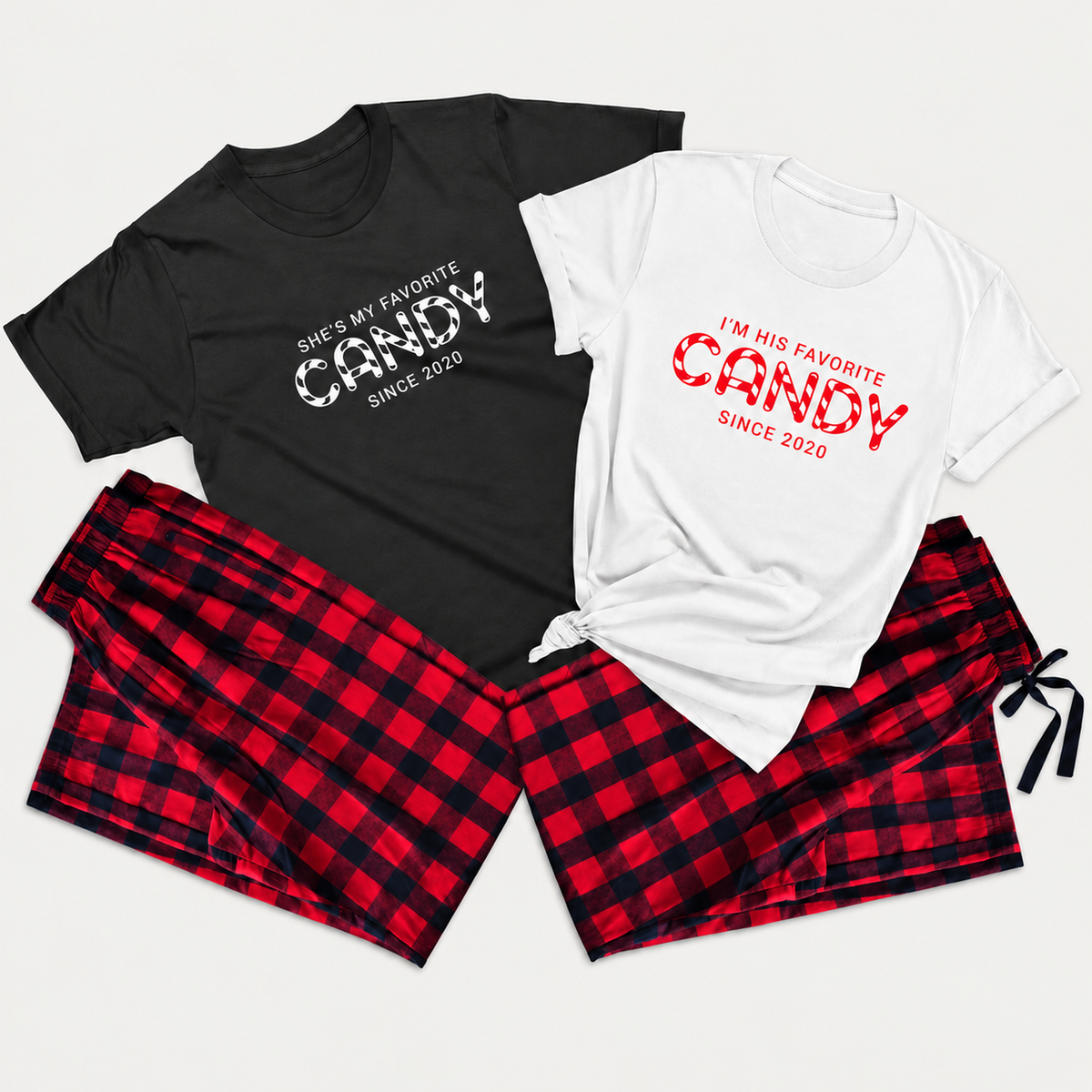Matching couple pajama set featuring black and white graphic T-shirts with “She’s My Favorite Candy” and “I’m His Favorite Candy” prints, paired with red and black buffalo plaid pajama bottoms arranged in a clean studio flat lay.