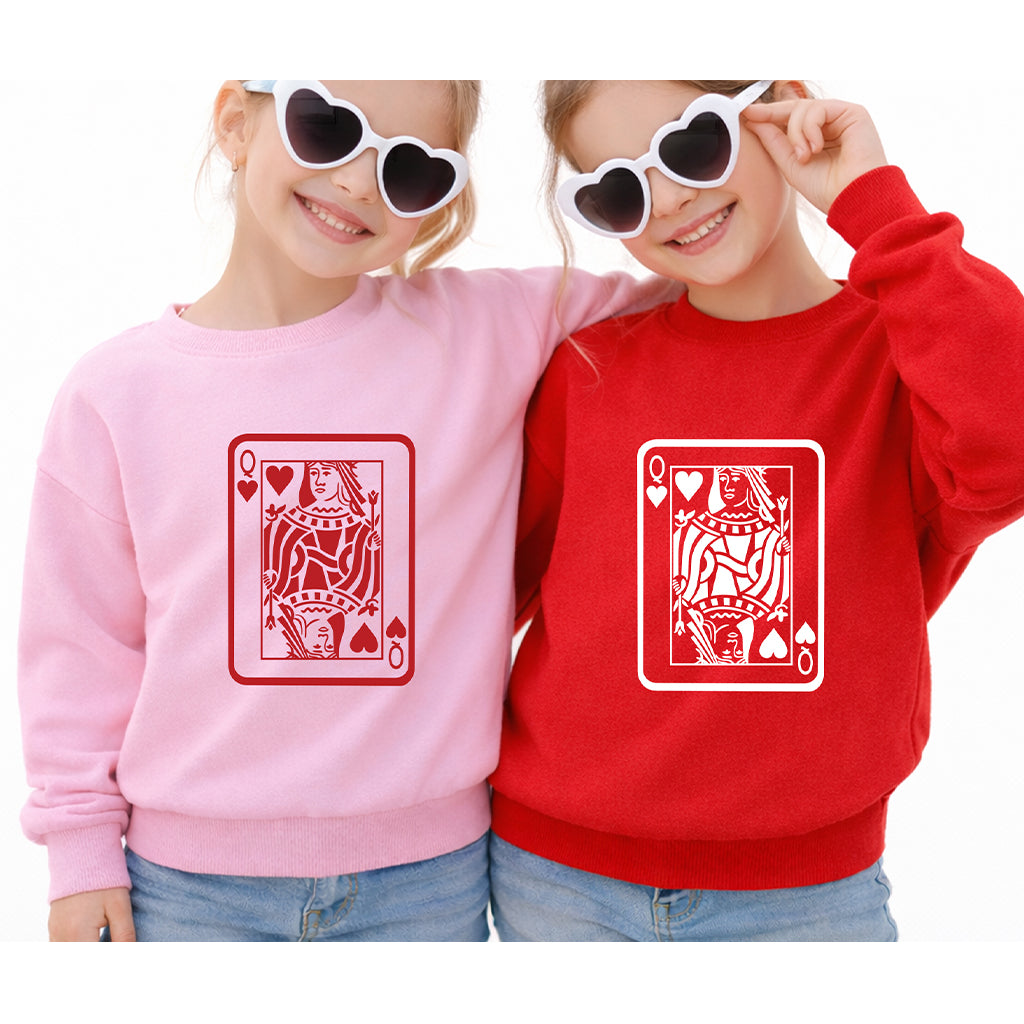 Toddler sisters wearing matching pink and red Queen card sweatshirts on white background for Valentine’s Day